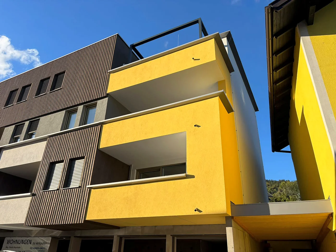 Aurea Wohnen von außen: gelbe Fassade mit Loggien bei blauem Himmel