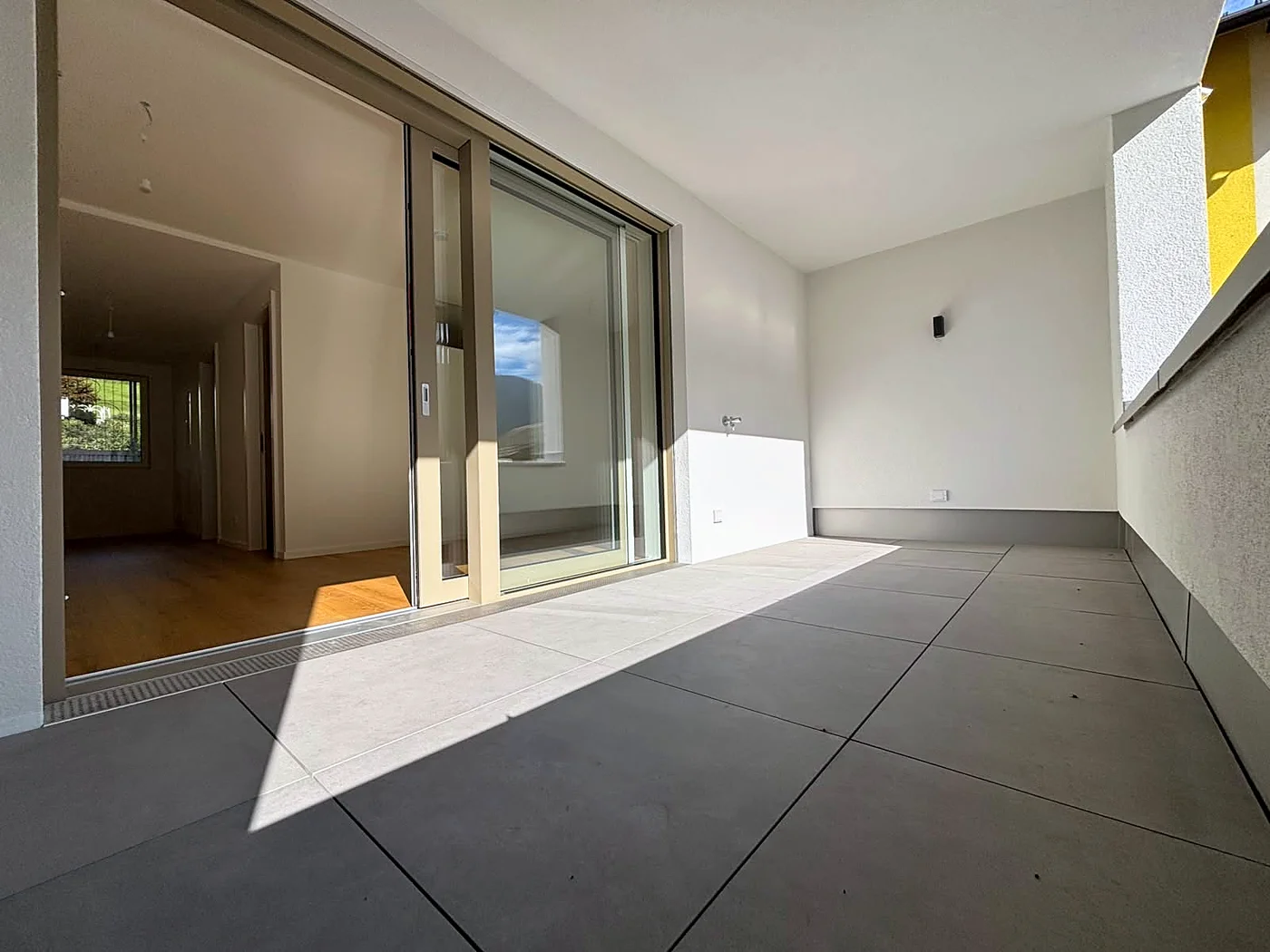 Überdachte Loggia mit Blick durch die Schiebetür in die Wohnung